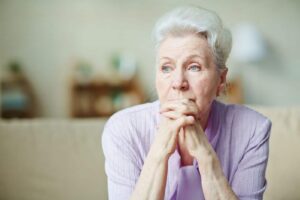 Elderly woman keeping hands by her lips